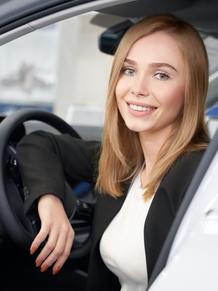 Portrait of attractive woman looking at camera in auto salon